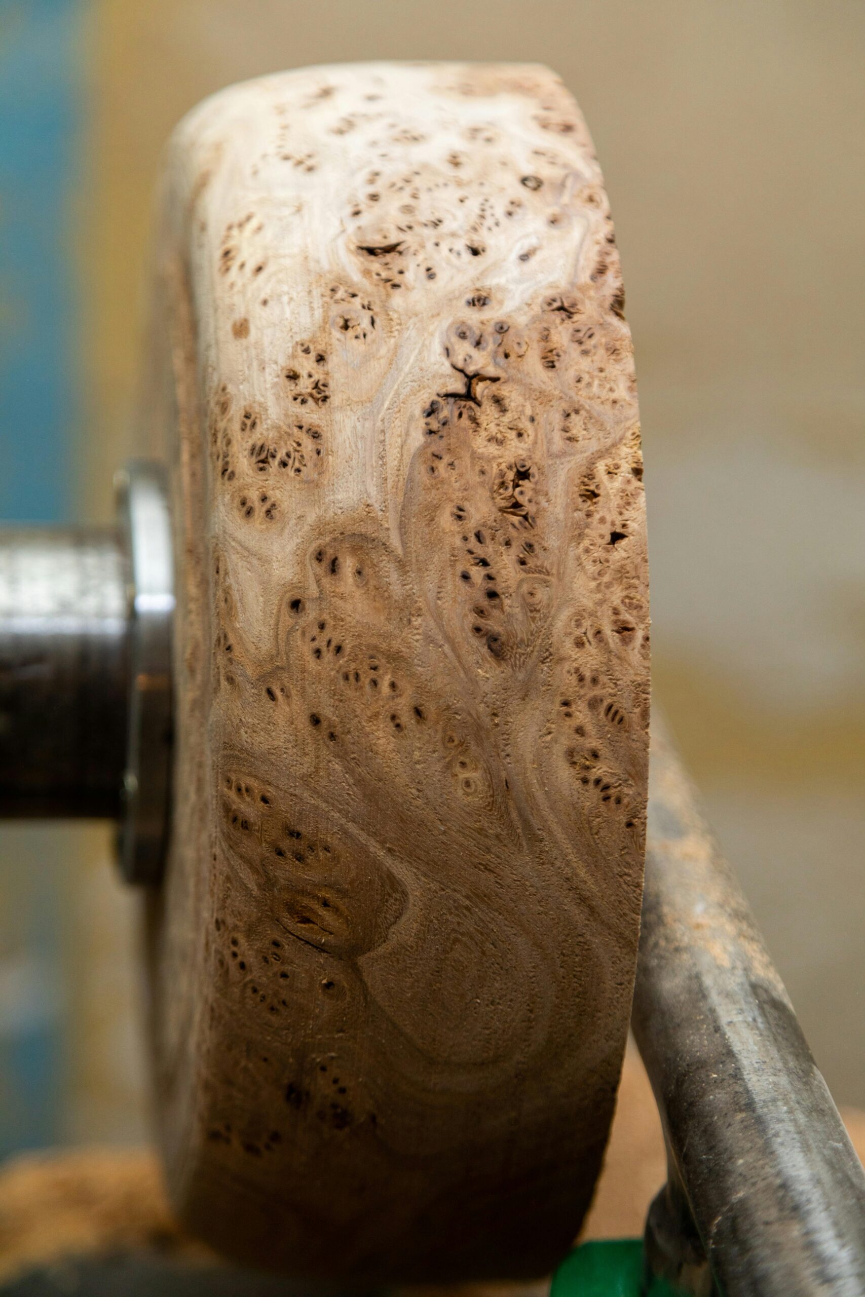 Detailed view of a wooden piece being crafted on a lathe, showcasing wood grain.